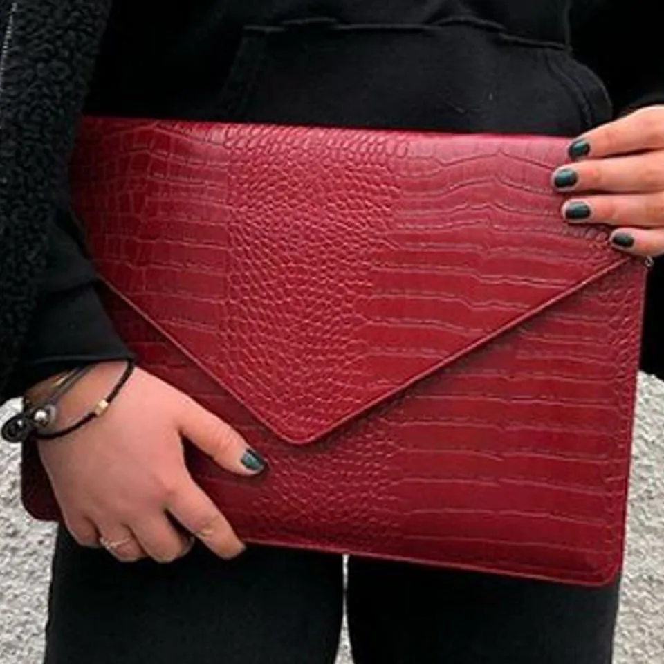Red crocodile-texture laptop sleeve carried by hand