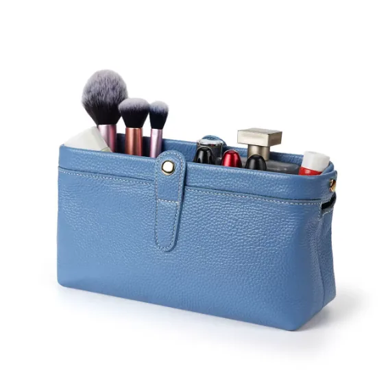Blue toiletry pouch shown holding brushes and cosmetics