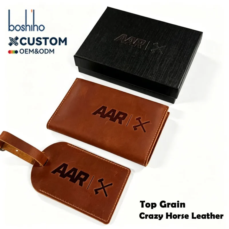 Brown leather passport cover and matching luggage tag beside a black gift box