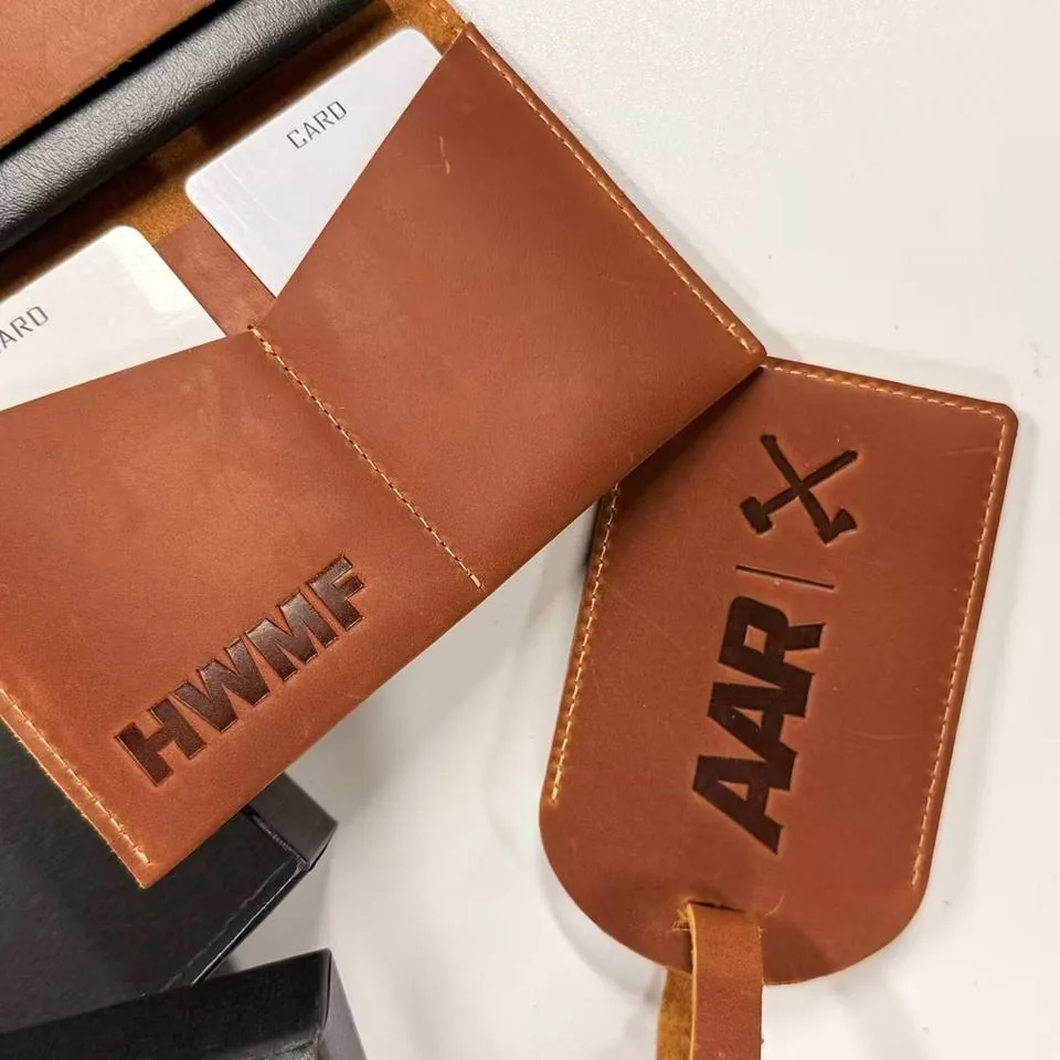 Open brown leather passport holder showing interior pockets beside a matching luggage tag